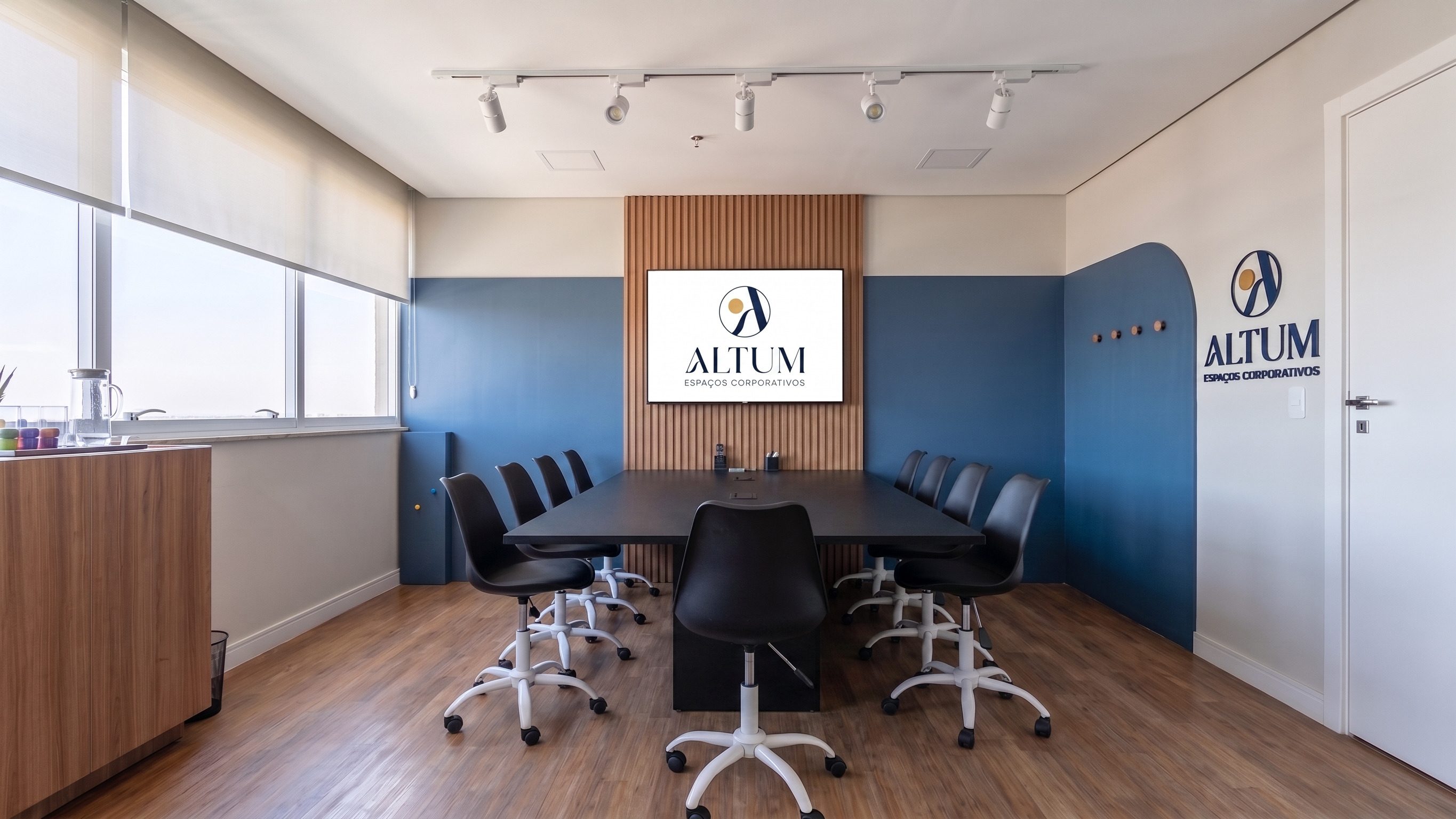 Sala ALTUM com painel ripado e TV, também usada para podcast